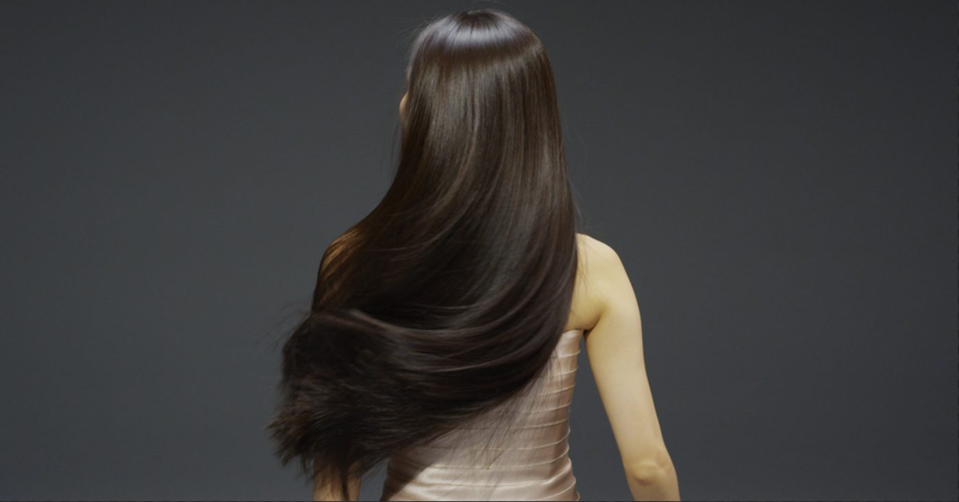 Long, glossy hair falling smoothly down the back, seen from behind